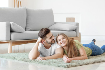 Obraz na płótnie Canvas Young couple resting on soft carpet at home
