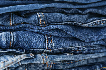 Stack of stylish jeans pants, closeup