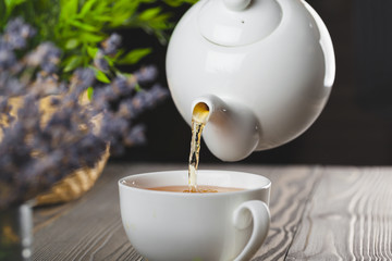 glass teapot with cup of black tea on wooden table