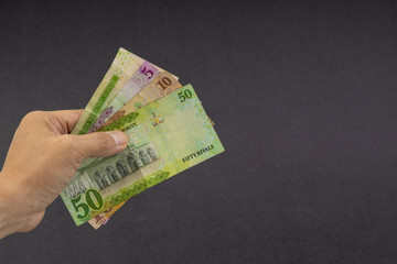 Hand holding saudi riyal bank notes on black background. Financial concept and selective focus