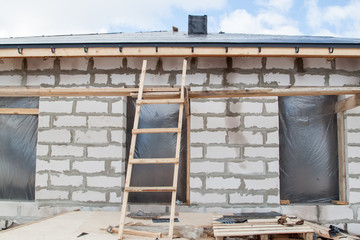 close up view of scaffolding and house under construction with holders for gutters water drainage system of roof