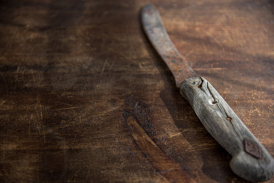 altes, rostiges Messer mit Holzgriff, isoliert auf rustikaler Tischplatte aus dunklem Holz