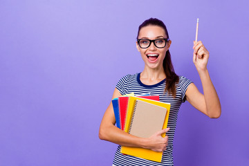 Portrait of her she nice attractive charming cute intelligent cheerful cheery girl holding in hands books pointing pencil up academic isolated over violet purple vivid shine bright background