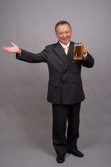 Portrait of mature Asian businessman against gray background