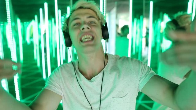 Young man rapper with headphones singing emotional in neon lights background