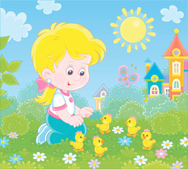 Little girl playing with small yellow chicks among flowers on green grass on a sunny summer day, vector illustration in a cartoon style