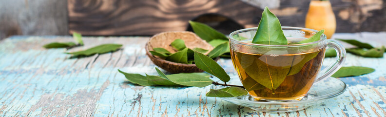 Fresh tea from bay leaf in a cup on a wooden rustic table. Copy space. Web banner