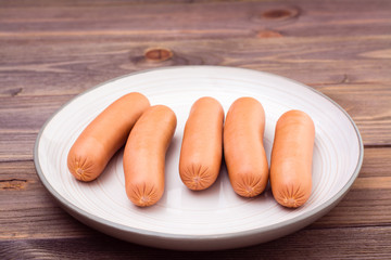 Boiled chicken sausages ready to eat on a plate on a wooden table