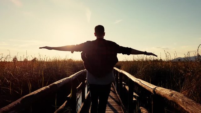 Silhouette di un ragazzo corre su un ponte di legno. Concetto di libert&agrave; e spensieratezza. Video al rallentatore.