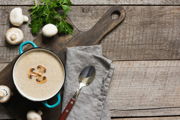 Delicious mushroom champignon soup on wooden board. View from above. Space for text.