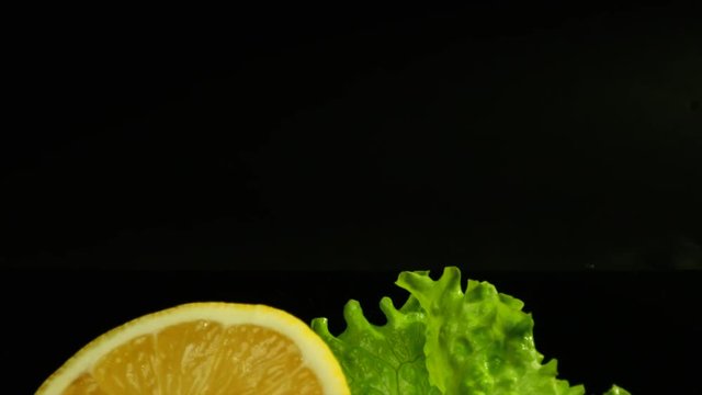 Commercial packshot of set of prawns, lemon and fresh salad on the black background