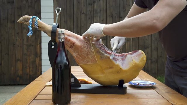 Traditional Jamon Serrano Ham full Leg from Spain being slicing with knife. Spanish Ham. Spain&rsquo;s national