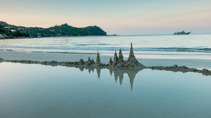 Sand tower castle and boats at the  beach of Phangan island Thailand