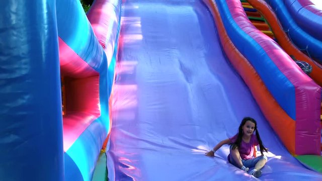 Child jumping on colorful playground trampoline. Kids jump in inflatable bounce castle on kindergarten birthday party Activity and play center for young child. Little girl playing outdoors in summer