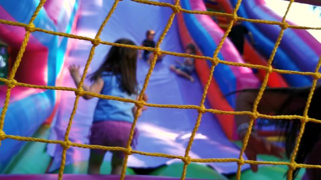 Child jumping on colorful playground trampoline. Kids jump in inflatable bounce castle on kindergarten birthday party Activity and play center for young child. Little girl playing outdoors in summer