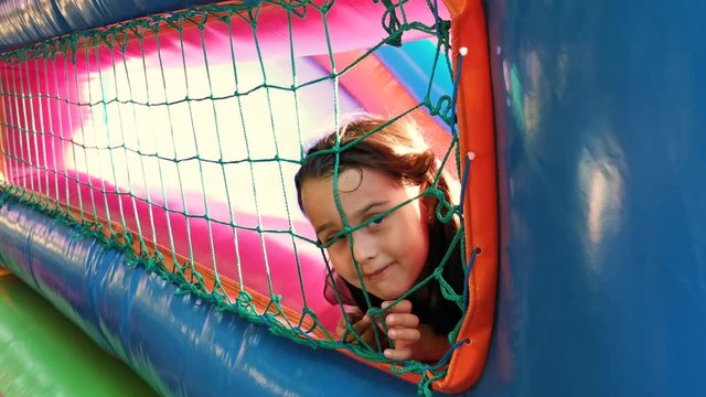 Child jumping on colorful playground trampoline. Kids jump in inflatable bounce castle on kindergarten birthday party Activity and play center for young child. Little girl playing outdoors in summer
