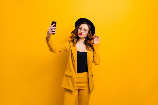 Close up photo beautiful funky she her lady arm hand arm telephone make take selfies send air kisses boyfriend leisure rejoice wear specs formal-wear costume suit isolated yellow vibrant background