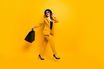 Full length side profile body size photo beautiful she her lady walking down street carry new clothes packs perfect look traveler wear specs formal-wear costume suit isolated yellow bright background