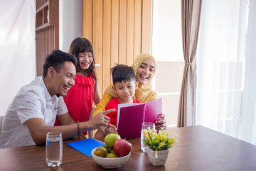 asian family reading a book together at home