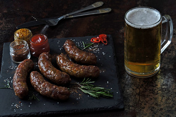 Hot sausages with spices and a glass of beer. Appetizing Bavarian sausages with beer.