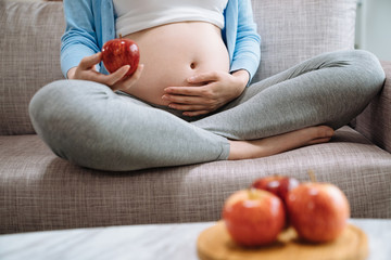 Ripe apple in hands of pregnant woman. Healthy food and drink body and healthcare concept of special mother to be period. focus close up on young asian girl holding belly with baby child motherhood