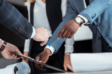 Naklejka premium cropped view of african american man gesturing near partner holding clipboard and pen