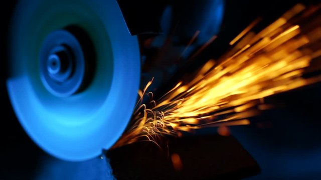 Close-up of welder grinding smooths steel and iron using modern equipment. Industrial production, locksmith industry concept. Sparks from grinding wheel.