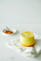 Healthy ayurvedic drink golden almond milk or pumpkin turmeric latte with curcuma powder on white background copy space.Trendy Asian natural detox beverage with spices for vegans.Alternative medicine