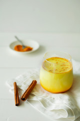 Healthy ayurvedic drink golden almond milk or pumpkin turmeric latte with curcuma powder on white background.Trendy Asian natural detox beverage with spices for vegans.Alternative medicine