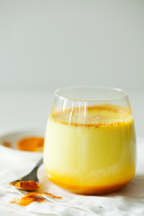 Healthy ayurvedic drink golden almond milk or pumpkin turmeric latte with curcuma powder on white...