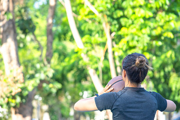 Naklejka na ściany i meble Asian Woman holding basketball Background blur tree in park.