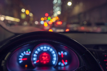 inside view of a taxi traveling through the city at night, windows lit with colorful lights, the facades of buildings are decorated with garlands © BarguZina