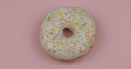 Sweet donut on pink background. Top view. Tasty, fresh sprinkled donut