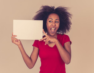 Young funny and excited african american woman in red holding blank board for advertisement.
