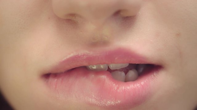 Female face with smiling mouth biting plump lips. Closeup woman biting sexy lips