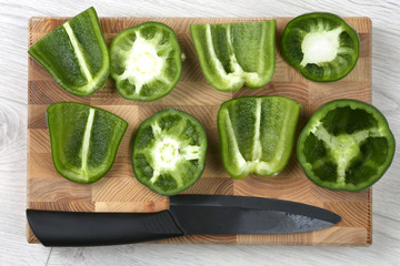 sliced sweet peppers with a ceramic knife on a wooden board