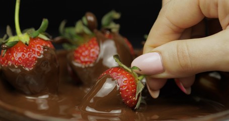 Hand dipping strawberry in melted chocolate. Fresh berries sweet dessert food