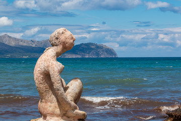stones on the beachsculpture of a woman made of stone by the sea and blue sky