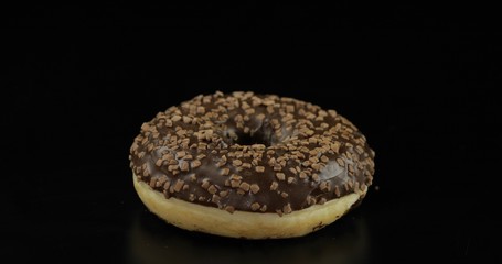 Sweet donut on black background. Tasty, fresh sprinkled donut
