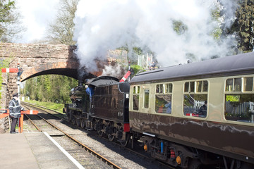 Fototapeta na wymiar Steam train just leaving the station on a heritage railway line, England, UK.