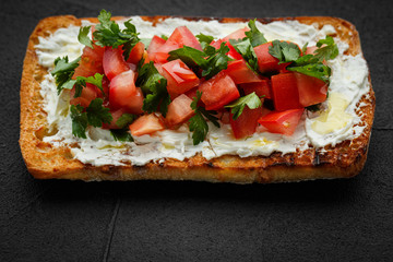 wholegraine ciabatta sandwich with sliced tomatoes, goat cheese, parsley. top view