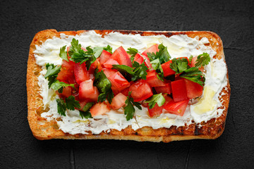 wholegraine ciabatta sandwich with sliced tomatoes, goat cheese, parsley. top view