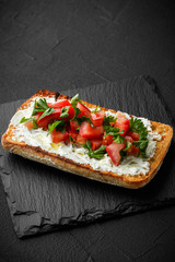 wholegraine ciabatta sandwich with sliced tomatoes, goat cheese, parsley. top view
