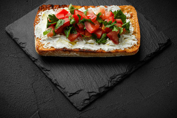 wholegraine ciabatta sandwich with sliced tomatoes, goat cheese, parsley. top view