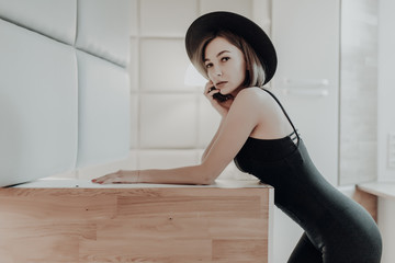 Young pretty woman in black hat and dress possing at home