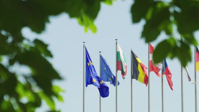 Calm peaceful view European Union flag next to other Eu Member states waving in front of Parliament headquarter in Strasbourg a day before 2019 European Parliament election view through trees