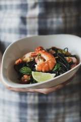 Black pasta with king prawns in a deep plate