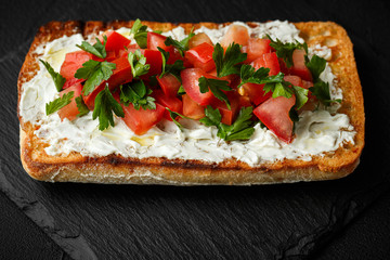 wholegraine ciabatta sandwich with sliced tomatoes, goat cheese, parsley. top view
