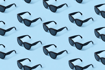 Fototapeta premium Black sunglasses pattern on pastel blue background.