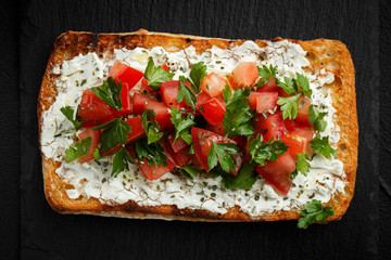 wholegraine ciabatta sandwich with sliced tomatoes, goat cheese, parsley. top view